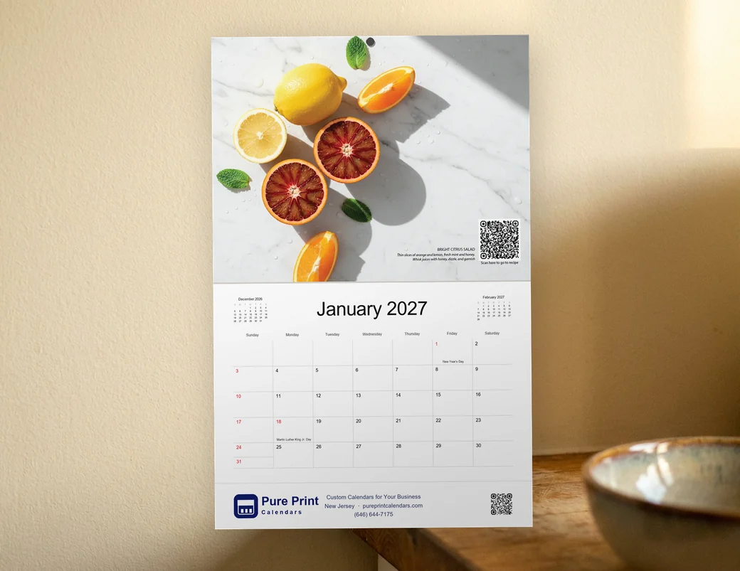 An In Season 2027 calendar hanging on a kitchen wall, open to January
